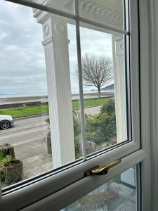 a window with a view of a road and a tree at Oyster Cottage in The Mumbles