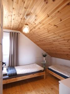 two beds in a room with a wooden ceiling at Domki Trzy - 3 in Smołdziński Las