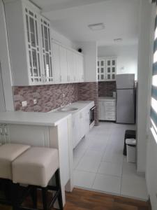 una cocina con armarios blancos y electrodomésticos blancos en ZOJA Apartments, en Kavadarci