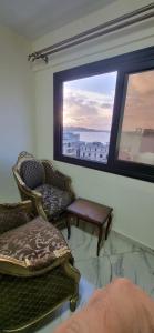 uma sala de estar com uma cadeira e uma janela em ستوديو على البحر محطة الرمل Raml station stodeo em Alexandria