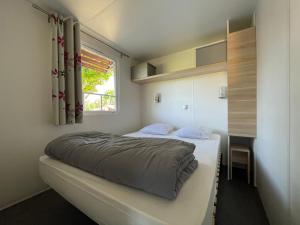 a small bedroom with a bed and a window at International Camping Ardèche in Salavas