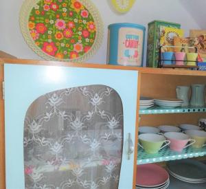 a shelf with plates and bowls and dishes on it at Retro Apartment Graz in Graz