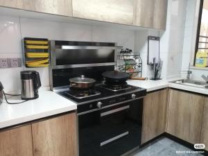 a kitchen with a stove with two pans on it at kayla泉州晋江吾悅广场五店市万达轻奢风投影3房 in Jinjiang