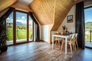 a dining room with a table and chairs and large windows at Apartamenty Widok Tatr in Zakopane
