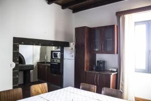 a kitchen with a table and chairs and a refrigerator at Casa Lagar de Pedra T3 in Santa Cruz da Graciosa