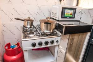 a kitchen with a stove with two pots and a microwave at Lux Suites Lumumba Drive Apartments in Nairobi +33 photos