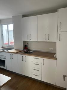 uma cozinha branca com armários brancos e um lavatório em Apartamento Arenas em Nerja