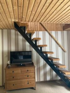 a wooden staircase in a room with a tv and a dresser at Ferienhaus Eichler in Bad Gottleuba