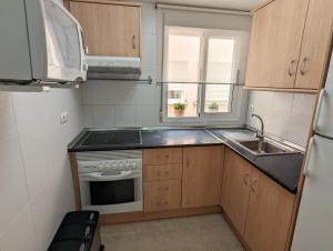 a small kitchen with a sink and a stove at Apartamento Las Palmeras - Con Terraza, barbacoa, aire acondicionado y a 250m de la playa! in Los Alcázares