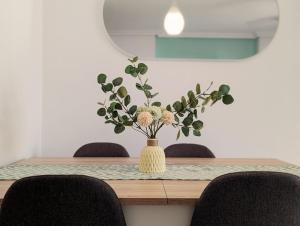 - une table à manger avec un vase fleuri dans l'établissement Apartamento Las Palmeras - Con Terraza, barbacoa, aire acondicionado y a 250m de la playa!, à Los Alcázares