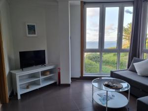 a living room with a couch and a tv and a table at Casa As Neves - 1B Gran Ventanal in Malpica