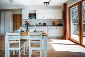 Apartamenty Widok Tatr في زاكوباني: مطبخ مع طاولة خشبية ودواليب بيضاء
