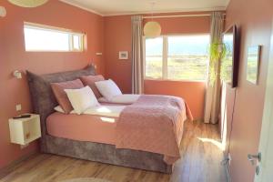 a bedroom with a bed with orange walls and a window at Austurey - Lakefront Villa in Laugarvatn