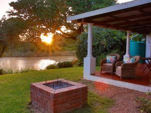 un patio con 2 sillas y una hoguera de ladrillo en Ndlovu Addo River Lodge en Kirkwood