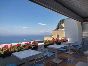 a patio with tables and flowers on a balcony at Piazzetta Diefenbach in Capri