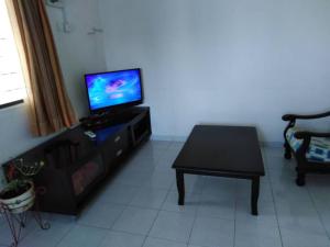 ein Wohnzimmer mit einem TV und einem Tisch in der Unterkunft 365 House by D'Laksamana in Malakka