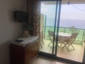 a room with a balcony with a table and a television at CANNES Front de mer in Cannes