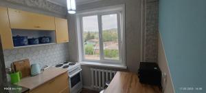 a kitchen with a stove and a window at LuxHome на УК in Ustʼ-Kamenogorsk