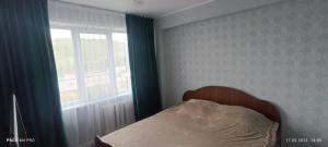 a bed in a bedroom with a window and a beditures sqor at LuxHome на УК in Ustʼ-Kamenogorsk