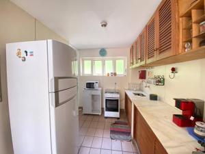 Una cocina con refrigerador blanco y gabinetes de madera. en Lindo 3 Qts com Deck churrasqueira Piscina Angra, en Angra dos Reis