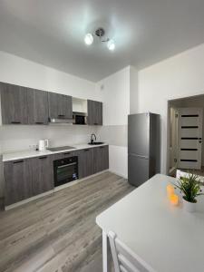 een keuken met een witte tafel en een koelkast bij Квартира однокомнатная in Taldykolʼ