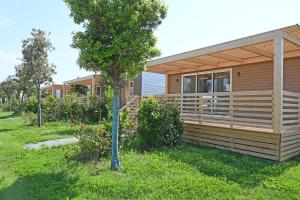 ein Holzhaus mit einer Veranda und einem Baum in der Unterkunft Agricampeggio Ippocampo in La Cinquantina