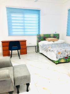 a bedroom with a bed and a desk and a chair at Mavern House Apartments in Elmina
