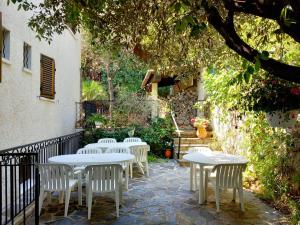d'une terrasse avec des tables et des chaises blanches sous un arbre. dans l'établissement Hôtel Cap Soleil, à Cavalaire-sur-Mer