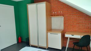 Zimmer mit einem Schrank, einem Schreibtisch und einer Ziegelwand in der Unterkunft Hostel Dzika Kaczka 