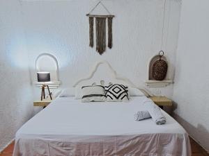 Una cama blanca con dos almohadas encima. en Apartamento Bizantino en Cozumel