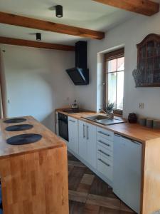 a kitchen with white cabinets and a wooden counter top at Wierzbowy zakątek Kąty Rybackie in Kąty Rybackie +7 photos