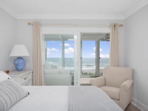 a bedroom with a bed and a chair and the ocean at El Mar Villa in Ponte Vedra Beach