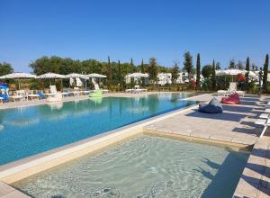 a large swimming pool with chairs and umbrellas at Agricampeggio Ippocampo in La Cinquantina