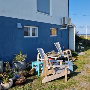 a patio with two chairs and a table in front of a blue wall at Liten leilighet i Berlevåg in Berlevåg