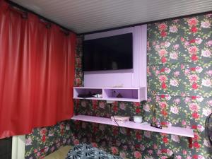 uma sala de estar com televisão numa parede floral em Barco Casa Pantanal Toca da Onça em Poconé