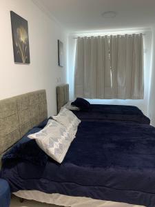 1 dormitorio con 1 cama con manta azul y ventana en Novíssimo apto no melhor de São Lourenço, en São Lourenço