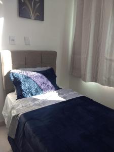 1 cama con edredón azul y almohada en Novíssimo apto no melhor de São Lourenço, en São Lourenço