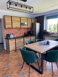 a kitchen with a wooden table and green chairs at Amonit in Olsztyn