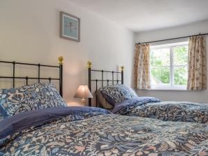 two beds in a bedroom with a window at Wayside Cottage in Adstock