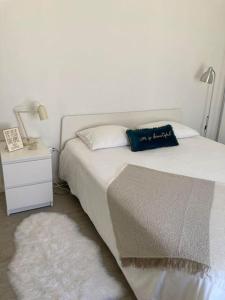 ein Schlafzimmer mit einem weißen Bett und einem Nachttisch mit einer Lampe in der Unterkunft Gafa House - Family Accommodation and Workplace in Gafanha da Nazaré