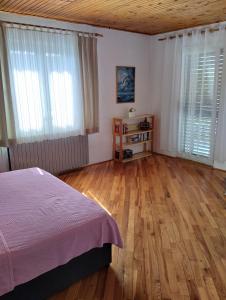 1 dormitorio con 1 cama, suelo de madera y ventanas en Ruža i Natalija en Karlobag
