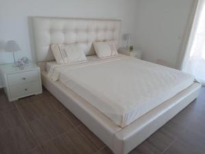 - un grand lit blanc avec une tête de lit blanche dans une chambre dans l'établissement IBAIA maison d'hôte, à Fnideq