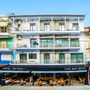 um grande edifício com mesas e cadeiras em frente em Hotel Zefyros em Paralia Katerinis