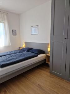 sypialnia z łóżkiem z niebieską pościelą i oknem w obiekcie Apartment Lori w mieście Matulji