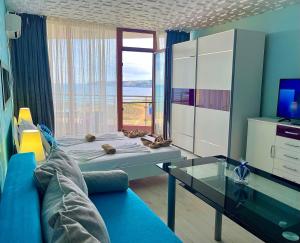 a living room with a blue couch and a large window at Свети Зосим in Sozopol