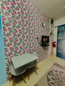 una habitación con una mesa y una pared cubierta de rosas en AD Homestay Gua Musang Terrace House with 3 room en Gua Musang
