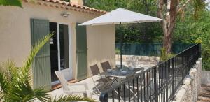 a patio with a table and an umbrella at Une maison en Provence in Pierrevert