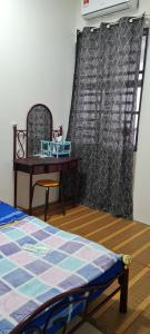 a bedroom with a bed and a table and a chair at DHut Homestay puncak iskandar in Seri Iskandar