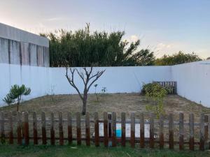 a wooden fence with a tree in front of a wall at Gafa House - Family Accommodation and Workplace in Gafanha da Nazaré