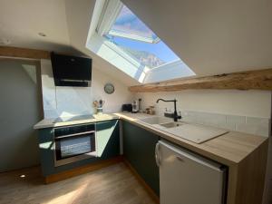 eine Küche mit einem Waschbecken und einem Dachfenster in der Unterkunft Appartement de charme au pied du Grand Colombier in Culoz